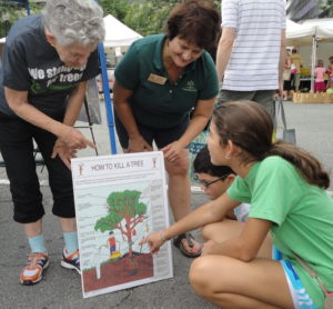 a picture of Tree Stewards showing children a poster with information about trees on it