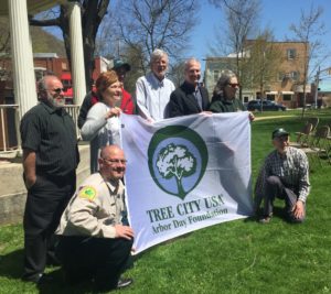 Group stands behind a Tree City USA banner with a large tree graphic on it.