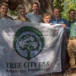 Urban forestry partners in Charlottesville Virginia hold up a flag for Tree City USA.