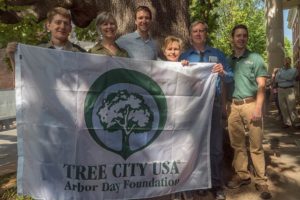 Urban forestry partners in Charlottesville Virginia hold up a flag for Tree City USA.